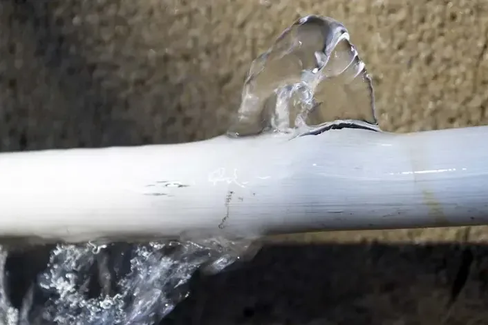 Water spraying out of a split plastic supply pipe