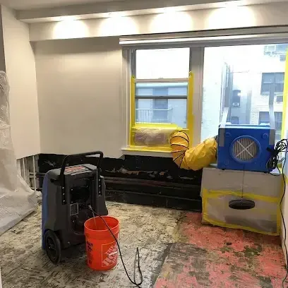 A dehumidifier and an air mover drying a room after the flooring was removed