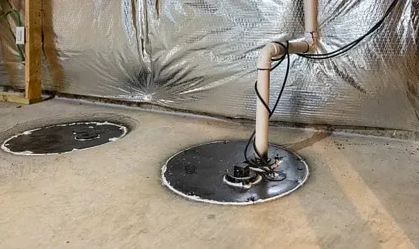 A sump pit with its pump discharge pipe tucked into a basement corner